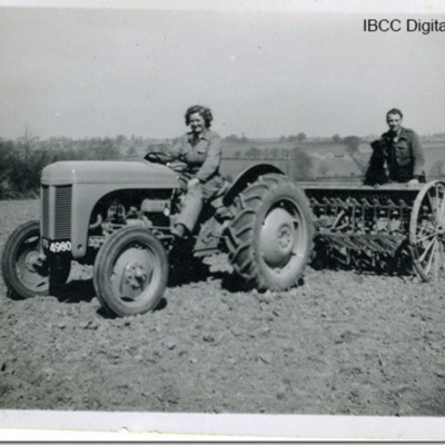 Margaret Tyler on  a tractor with a prisoner of war