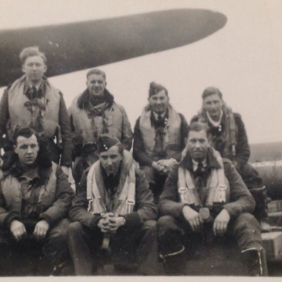 Seven aircrew sitting on a bomb trolley
