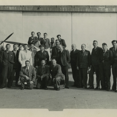 Large group of men in front of a hangar