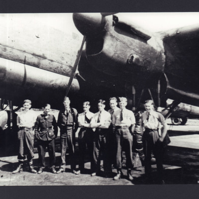 Eight airmen standing below a Lancaster 