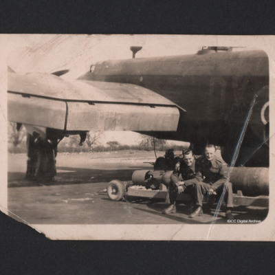Two men sitting on a bomb trolley