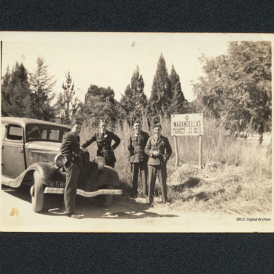 Four airmen standing by a car
