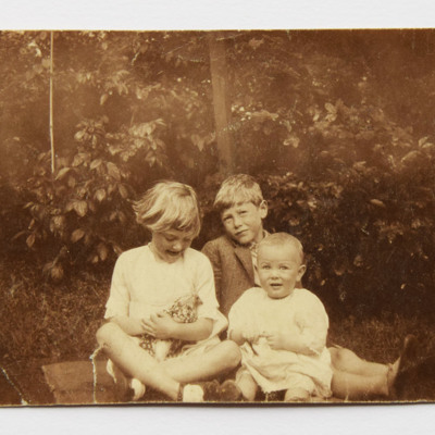 Three children sitting on ground