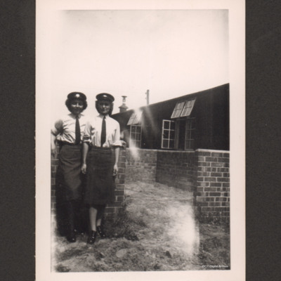 Two members of the Woman&#039;s Auxiliary Air Force standing by a brick wall